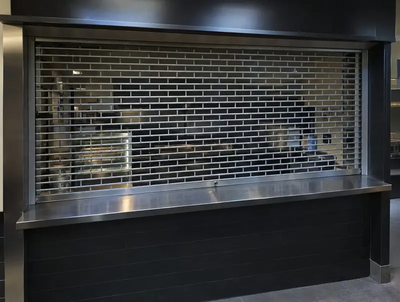 Compact roller grille closed over a serving hatch above a steel counter