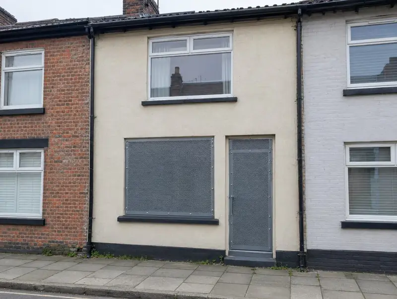 Empty terraced house with perforated steel screens over the window and door